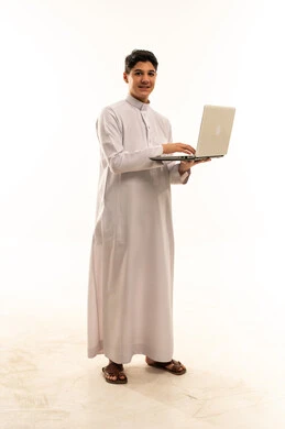 مراهق سعودي بالثوب التقليدي يحمل لابتوب
