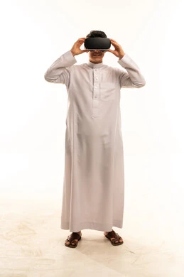 رجل سعودي بالثوب الأبيض يستخدم نظارة الواقع الافتراضي