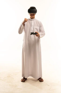 شاب سعودي يرتدي نظارة واقع افتراضي ويستخدم جهاز تحكم