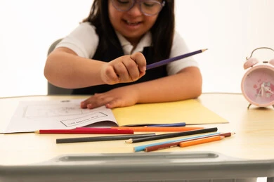 طالبة من ذوي متلازمة داون ترسم على المكتب المدرسي