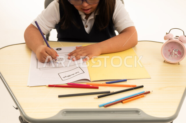 Saudi Girl with Down Syndrome Coloring at School Desk