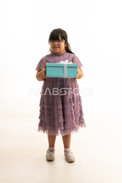 طفلة سعودية من ذوي الاحتياجات الخاصة مع صندوق هدايا