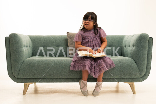 Saudi Girl with Down Syndrome Reading on Green Sofa