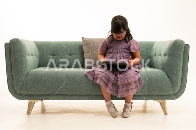 Arab Girl with Down Syndrome Using Tablet on Sofa