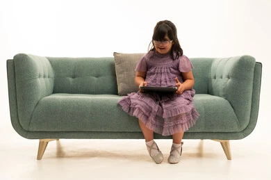 Saudi Girl with Down Syndrome Using Tablet on Sofa