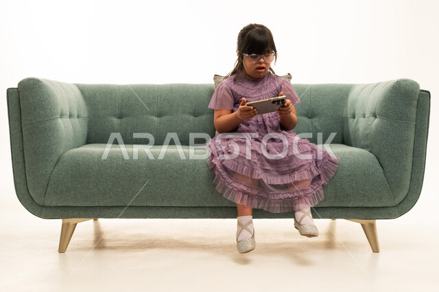 Saudi Girl with Down Syndrome Using Smartphone on Sofa