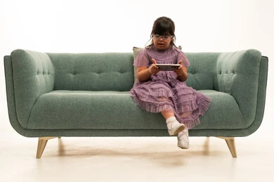Saudi Girl with Down Syndrome Using Smartphone on Sofa