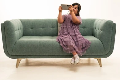 Saudi Girl with Down Syndrome Using Smartphone on Sofa