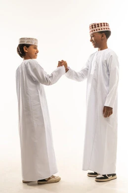أطفال عمانيون بالزي التقليدي يتصافحان باليد