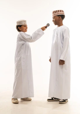 أطفال عمانيون بالزي التقليدي مع ميكروفون مقابلة