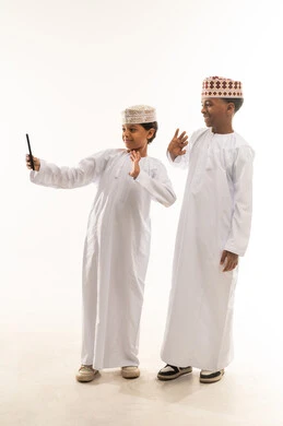 أطفال عمانيون بالزي التقليدي مع هاتف ذكي