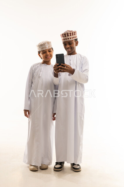 أطفال عمانيون باللباس التقليدي يستخدمون الهاتف