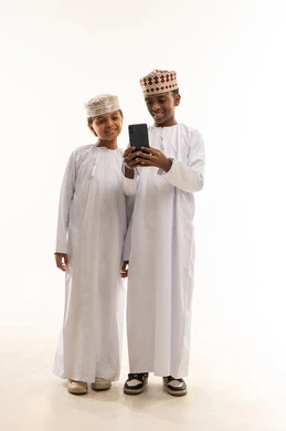 أطفال عمانيون باللباس التقليدي يستخدمون الهاتف