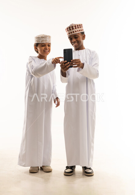 أطفال عمانيون بالزي التقليدي يستخدمون الهاتف الذكي