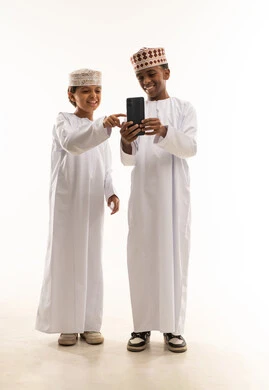 أطفال عمانيون بالزي التقليدي يستخدمون الهاتف الذكي