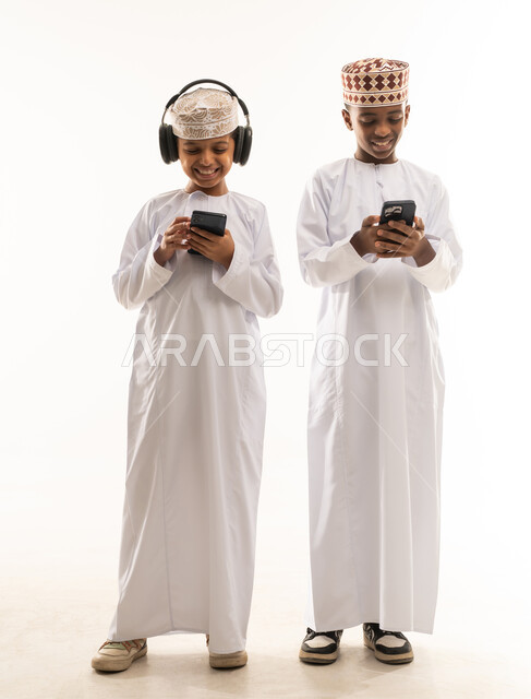 أطفال عمانيون بالزي التقليدي يستخدمون الهواتف الذكية