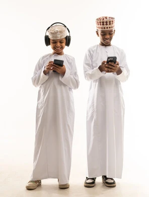 أطفال عمانيون بالزي التقليدي يستخدمون الهواتف الذكية