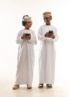 أطفال عمانيون بالزي التقليدي مع هواتف ذكية خلفية بيضاء