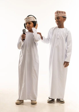 أطفال عمانيون بالزي التقليدي مع ميكروفون وسماعات