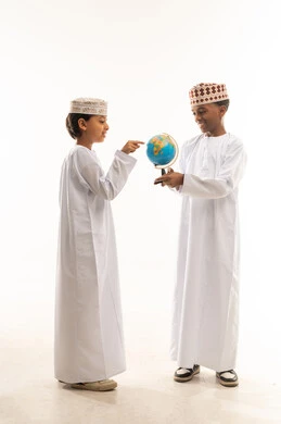Omani Boys in Traditional Dress Examining World Globe