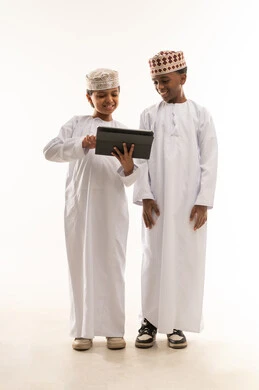 أطفال عمانيون يستخدمون جهاز لوحي بالزي التقليدي