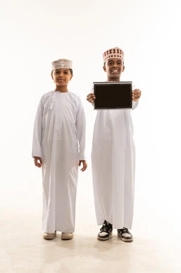 Omani Boys in Traditional Dress Holding Tablet