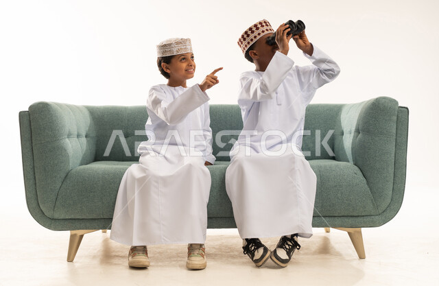 أطفال عمانيون بالزي التقليدي يستخدمون المنظار