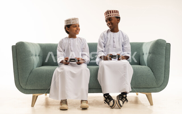 أطفال عمانيون بالزي التقليدي يلعبون ألعاب الفيديو