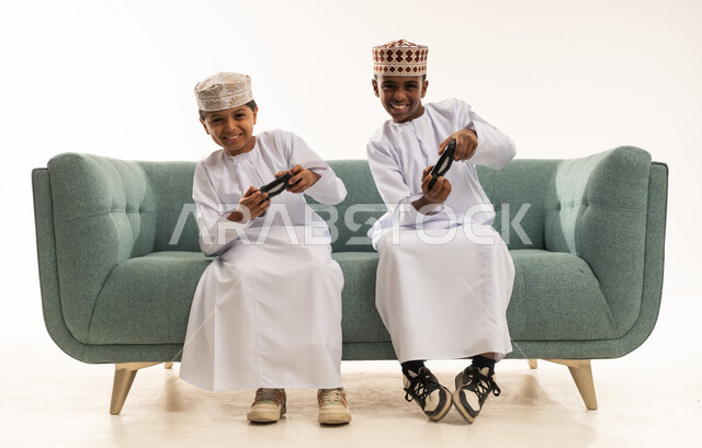 أطفال عمانيون يلعبون ألعاب الفيديو على أريكة