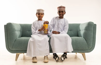 أطفال عمانيون بالزي التقليدي يأكلون الفشار