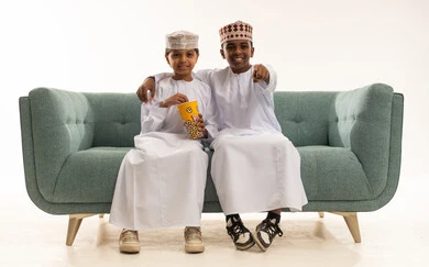 Omani Boys in Traditional Dress on Sofa with Popcorn