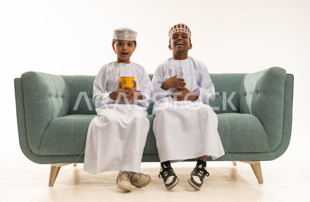 أطفال عمانيون بالزي التقليدي على أريكة في استوديو