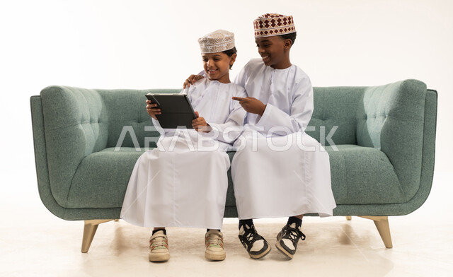 أطفال عمانيون بالزي التقليدي يستخدمون جهاز لوحي