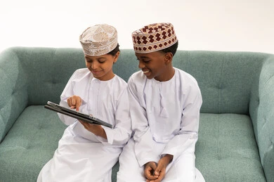 Omani Children in Traditional Clothing Using Tablet