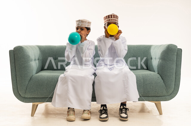 أطفال عمانيون بالزي التقليدي ينفخون البالونات