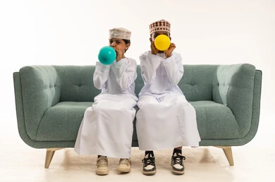 أطفال عمانيون بالزي التقليدي ينفخون البالونات