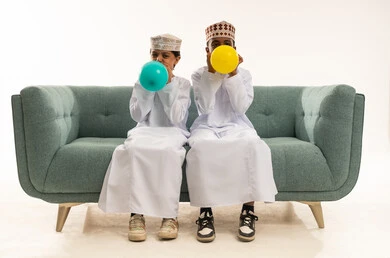 Omani Boys in Traditional Dress Blowing Balloons