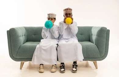 Omani Boys Blowing Balloons on Sofa in Studio