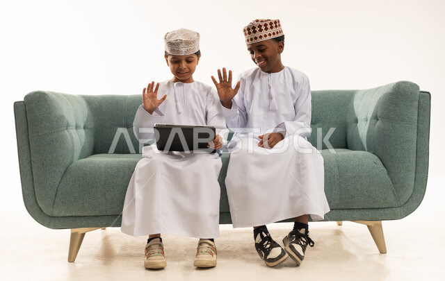 أطفال عمانيون بالزي التقليدي يستخدمون جهاز لوحي