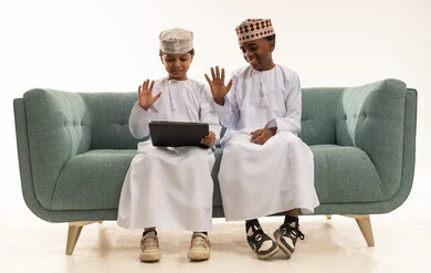 Omani Boys in Traditional Dress Using Tablet on Sofa