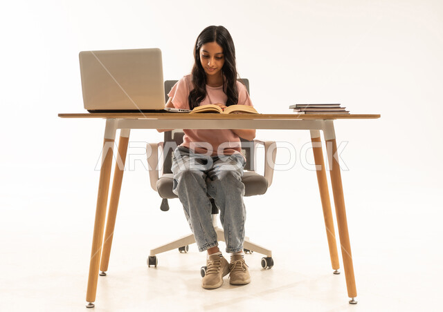 Saudi Woman Student Reading at Desk with Laptop