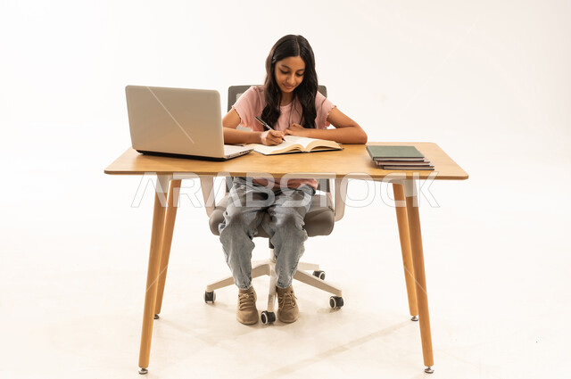 Arab Girl Student Writing at Desk with Laptop