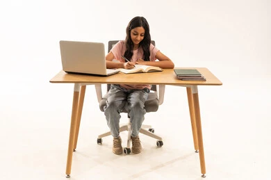 طالبة عربية تكتب على المكتب مع كمبيوتر محمول