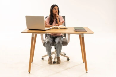 طالبة عربية تفكر على المكتب مع حاسوب محمول