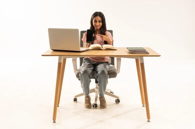 فتاة سعودية تشير إلى هاتف ذكي على مكتب الدراسة