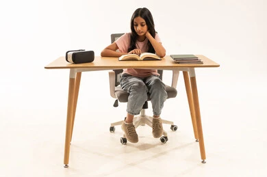 فتاة عربية تقرأ كتاباً على مكتب مع نظارة واقع افتراضي