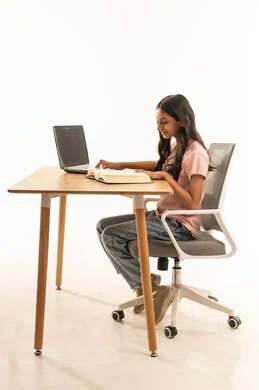 فتاة سعودية تدرس باستخدام المحمول على مكتب خشبي