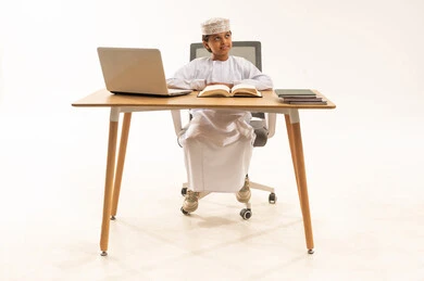 Omani Boy in Traditional Dress Studying at Desk