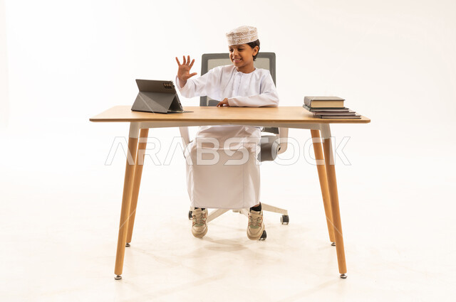طفل عماني يلوح لجهاز لوحي في استوديو