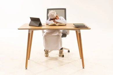 Omani Boy Sleeping on Study Desk with Books